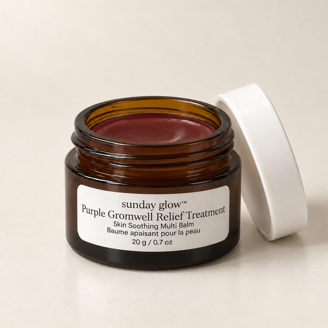 An open amber glass jar of Sunday Glow Purple Gromwell Relief Treatment with its white lid leaning against it, set against a warm beige background.
